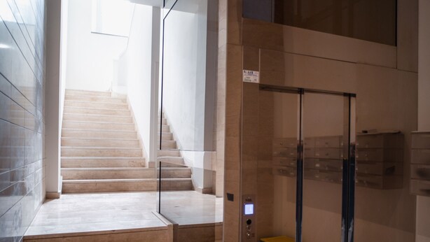 Un intérieur moderne avec un ascenseur en verre, un escalier et un design épuré et minimaliste.
