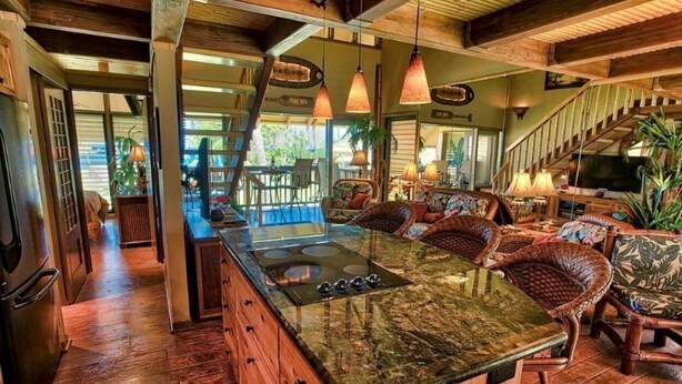 Un'ampia cucina con un'isola grande, pavimento in legno e lampade a sospensione.