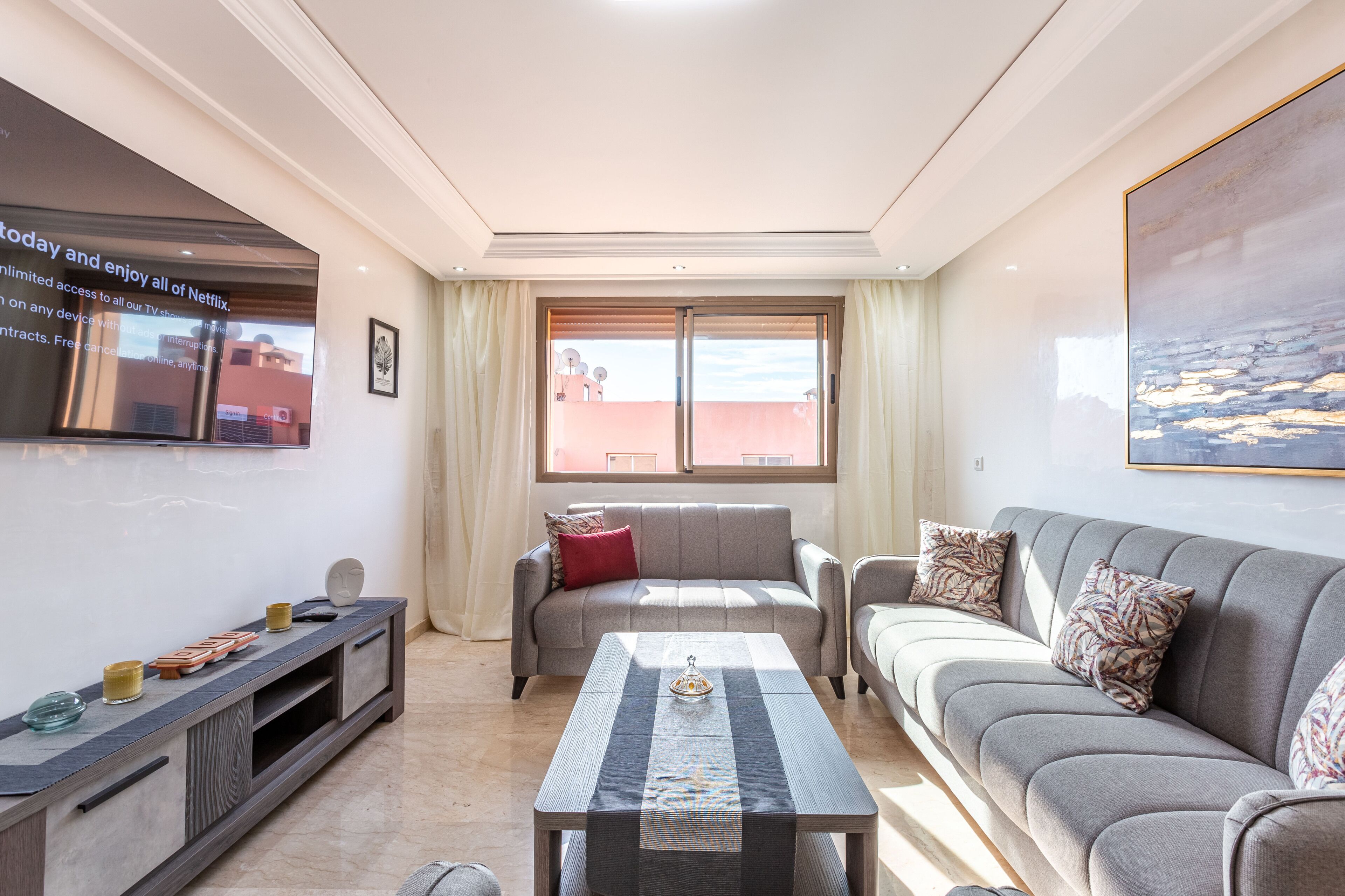 A modern living room with a flat-screen TV, a sofa set, a coffee table, and a TV stand.