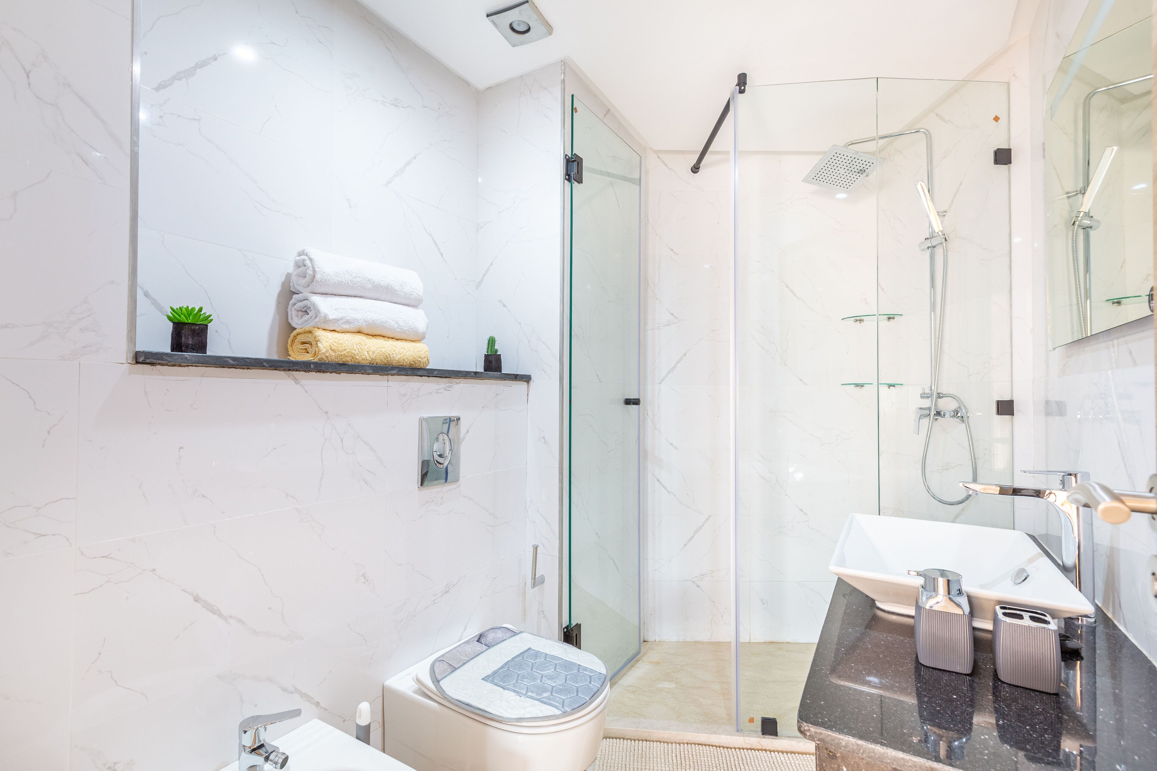 A modern bathroom with a glass shower enclosure, a vanity with a sink, and a toilet.