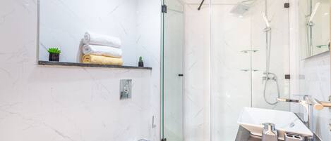 A modern bathroom with a glass shower enclosure, a vanity with a sink, and a toilet.