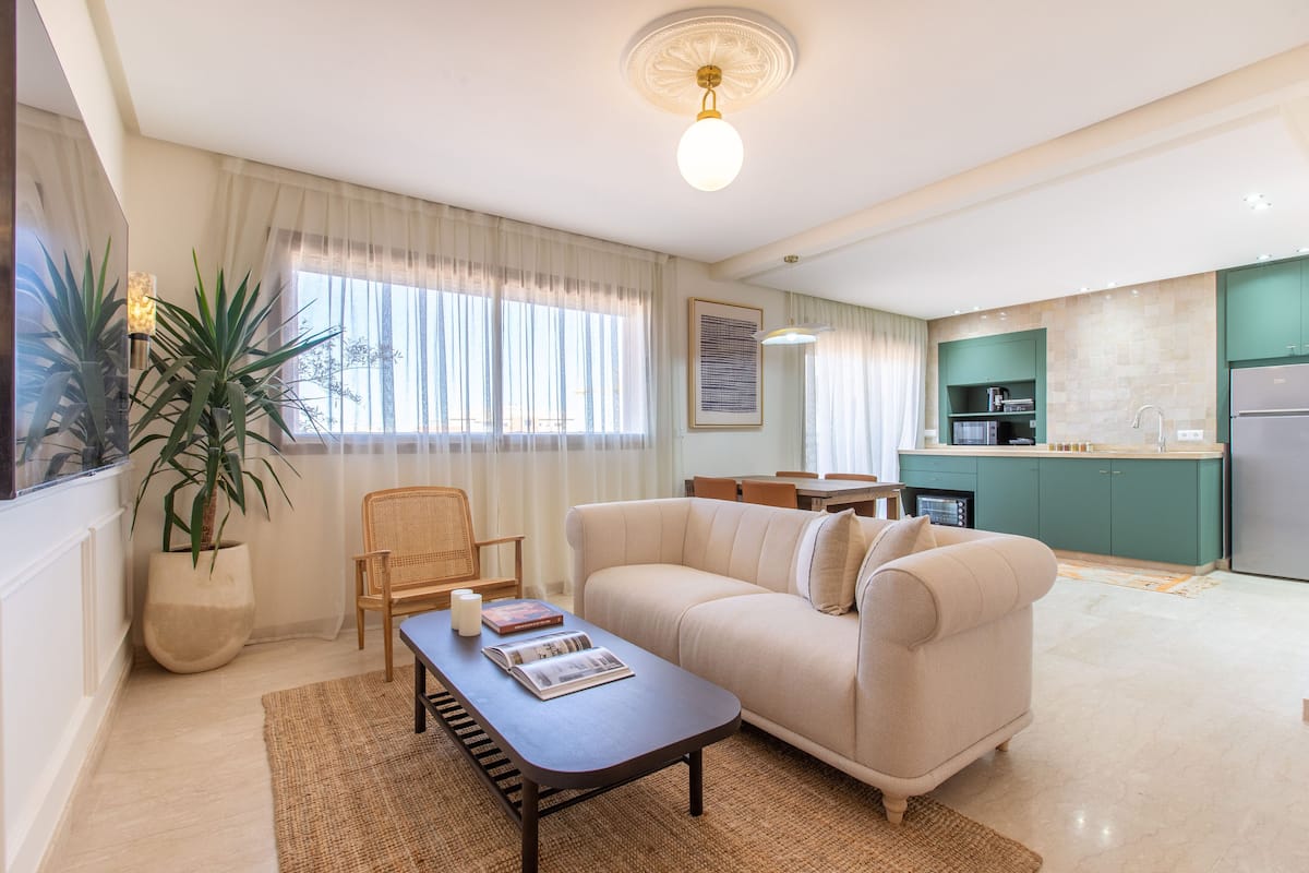 A modern living room with a sofa, coffee table, and a dining area.