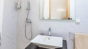 Un baño moderno con ducha, lavamanos e inodoro.