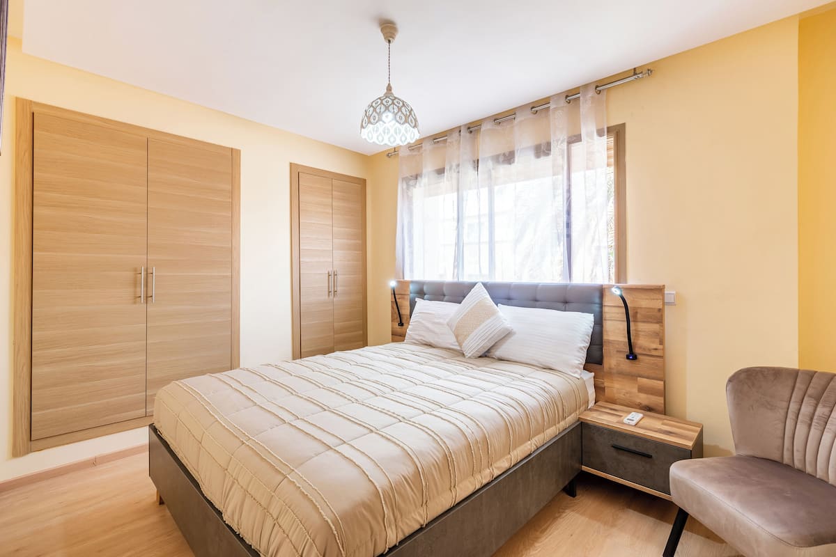 A bedroom with a bed, nightstands, a chair, and a wardrobe.