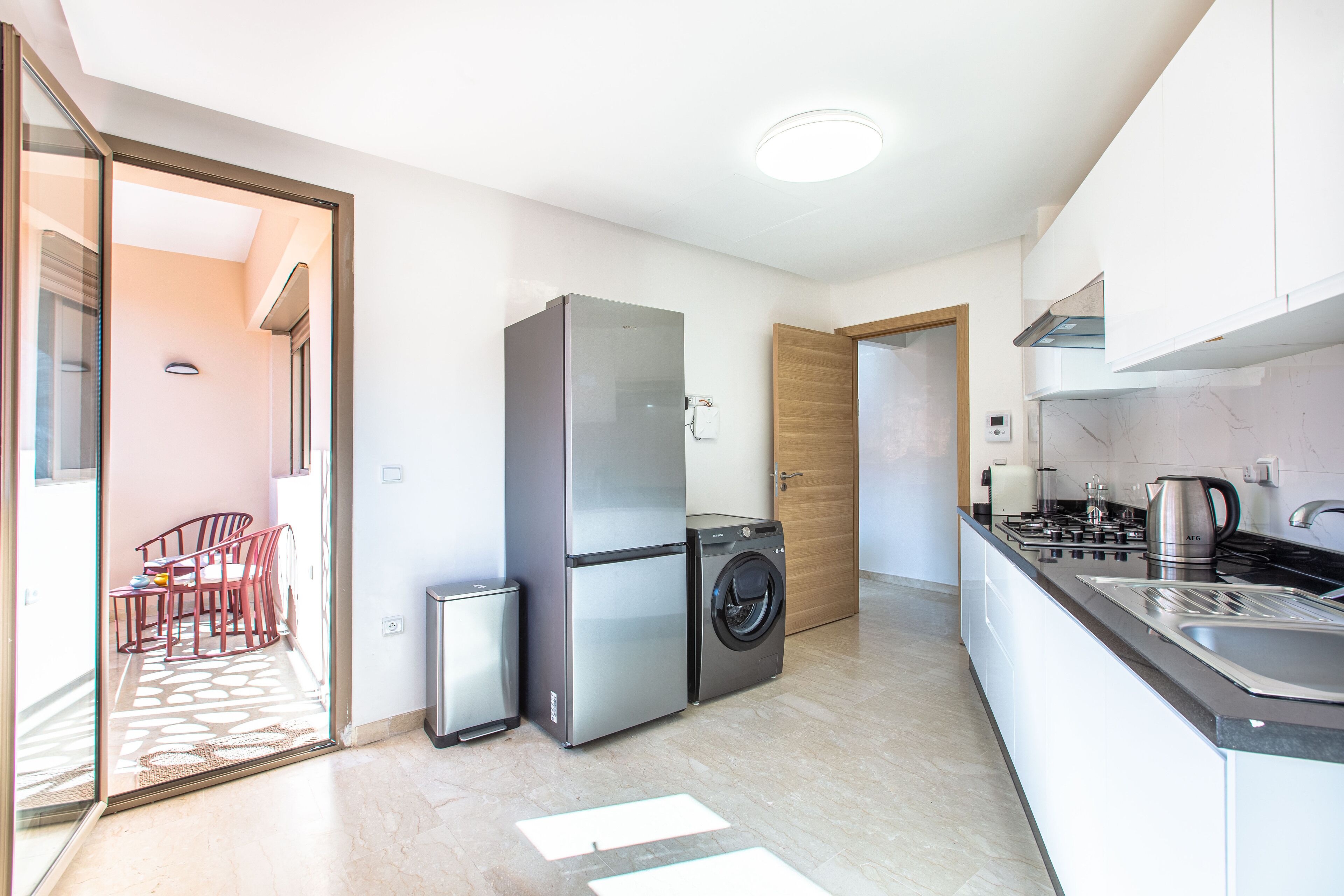 A compact kitchen with a refrigerator, washing machine, and a stove.