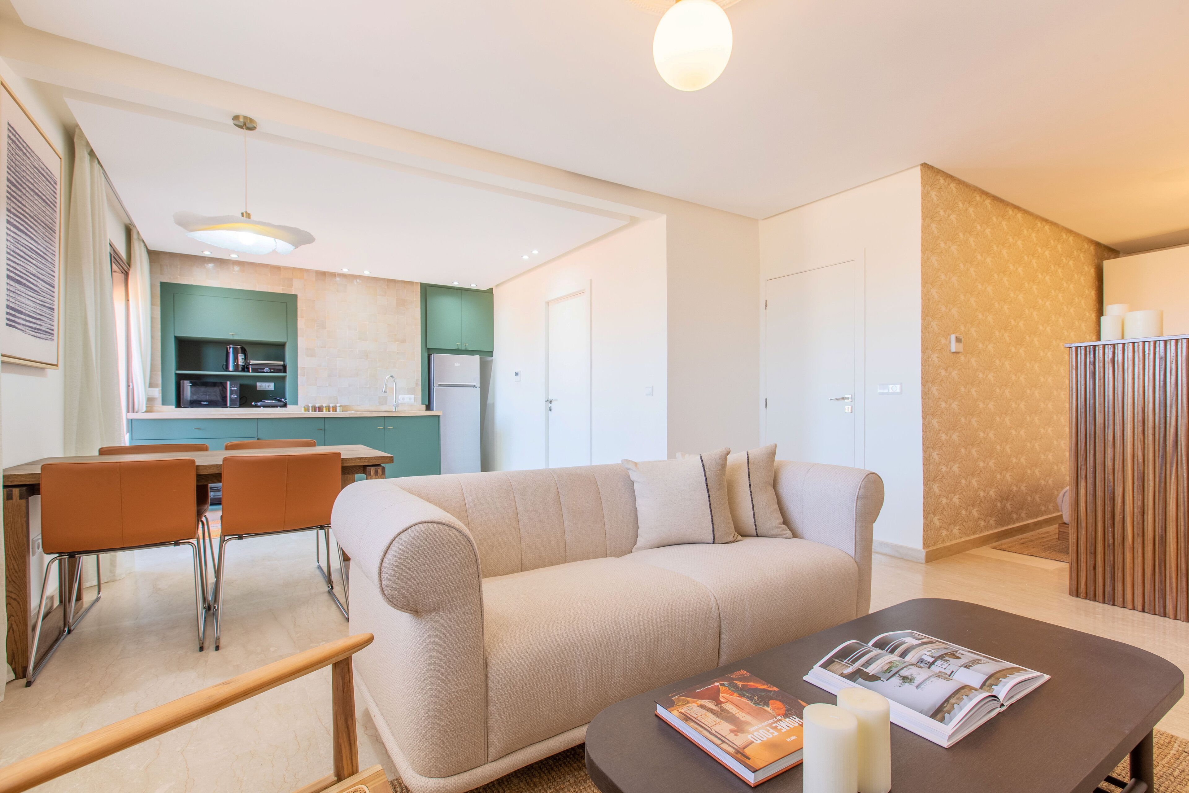 A modern living room with a sofa, a coffee table with magazines, and a dining area with chairs and a table.