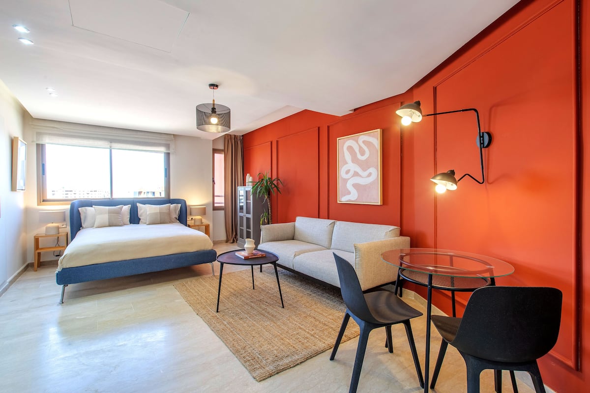 A modern bedroom with a bed, a sofa, a glass table, and a chair.