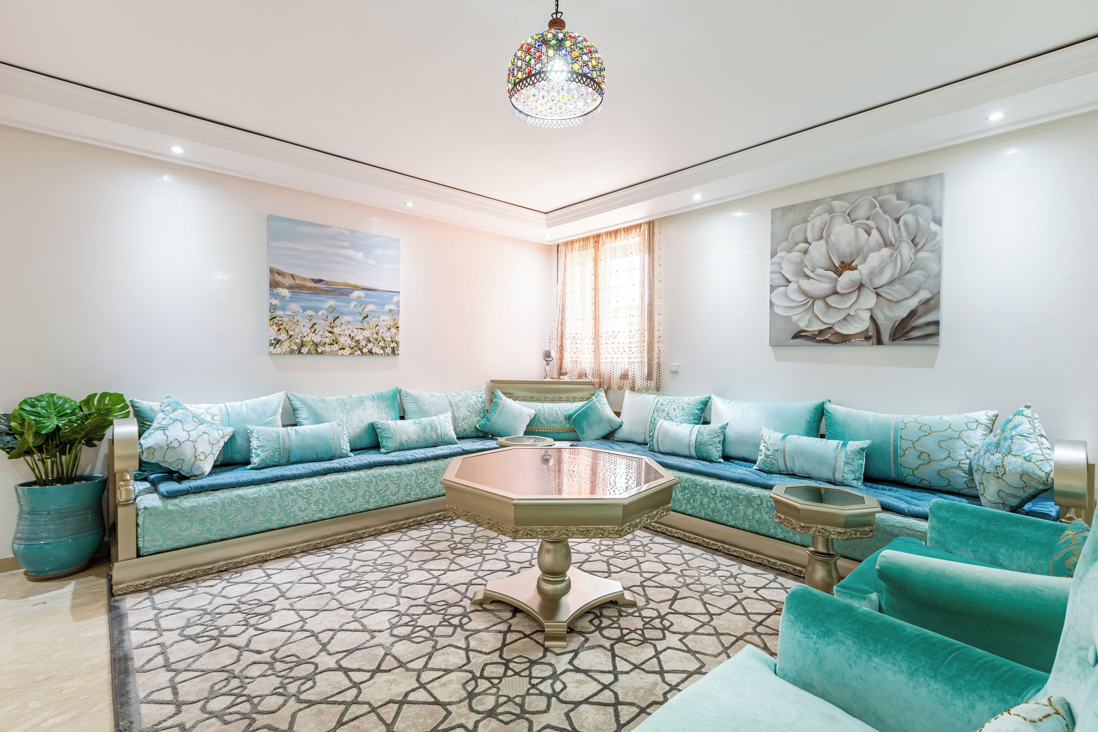 Una sala moderna con un sofá modular, una mesa de centro y un cuadro grande con motivos florales en la pared.