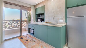 Una cocina moderna con armarios color turquesa, un refrigerador de acero inoxidable y un amplio ventanal con vistas a la ciudad.
