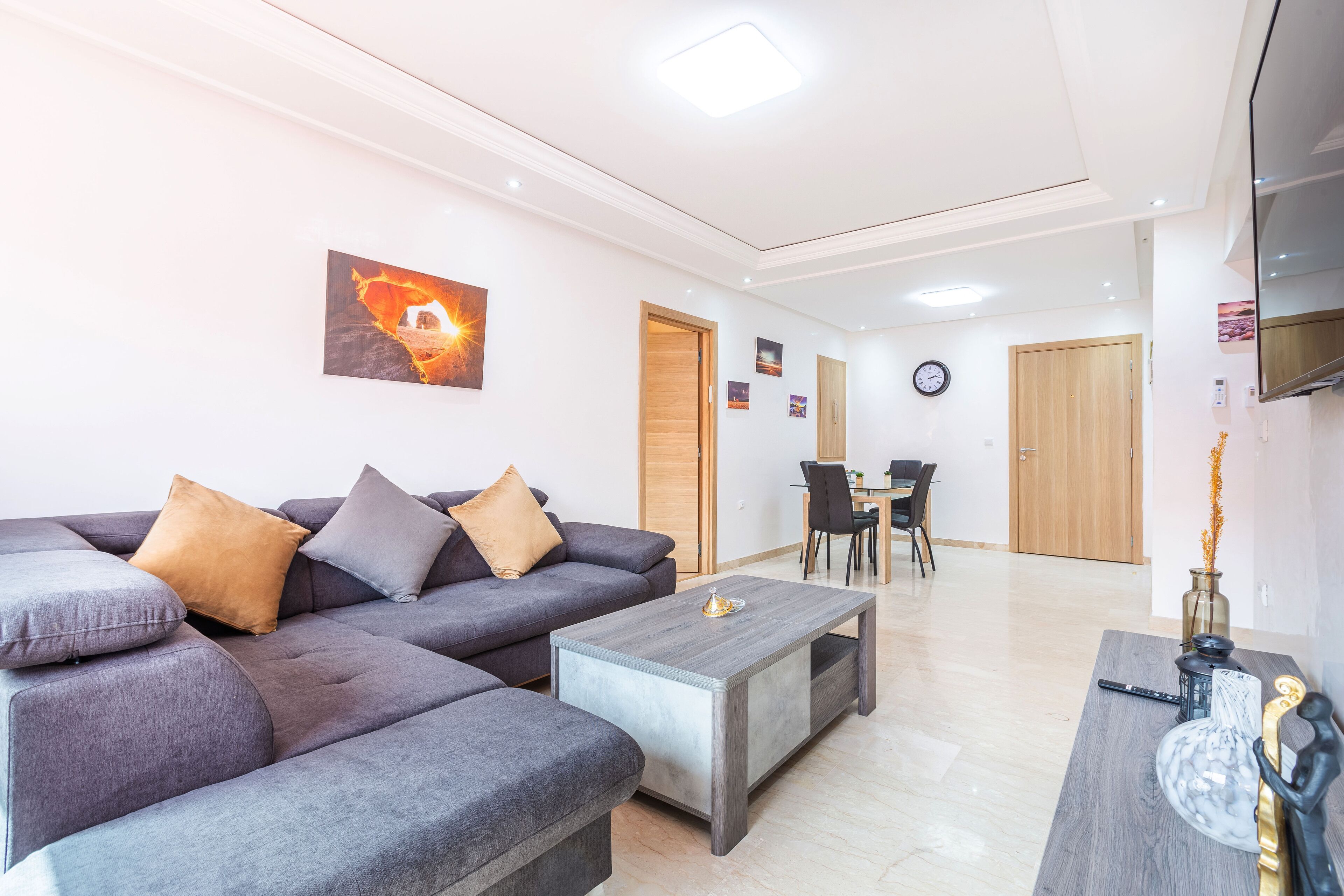 A modern living room with a sectional sofa, a coffee table, and a dining area with chairs and a table.