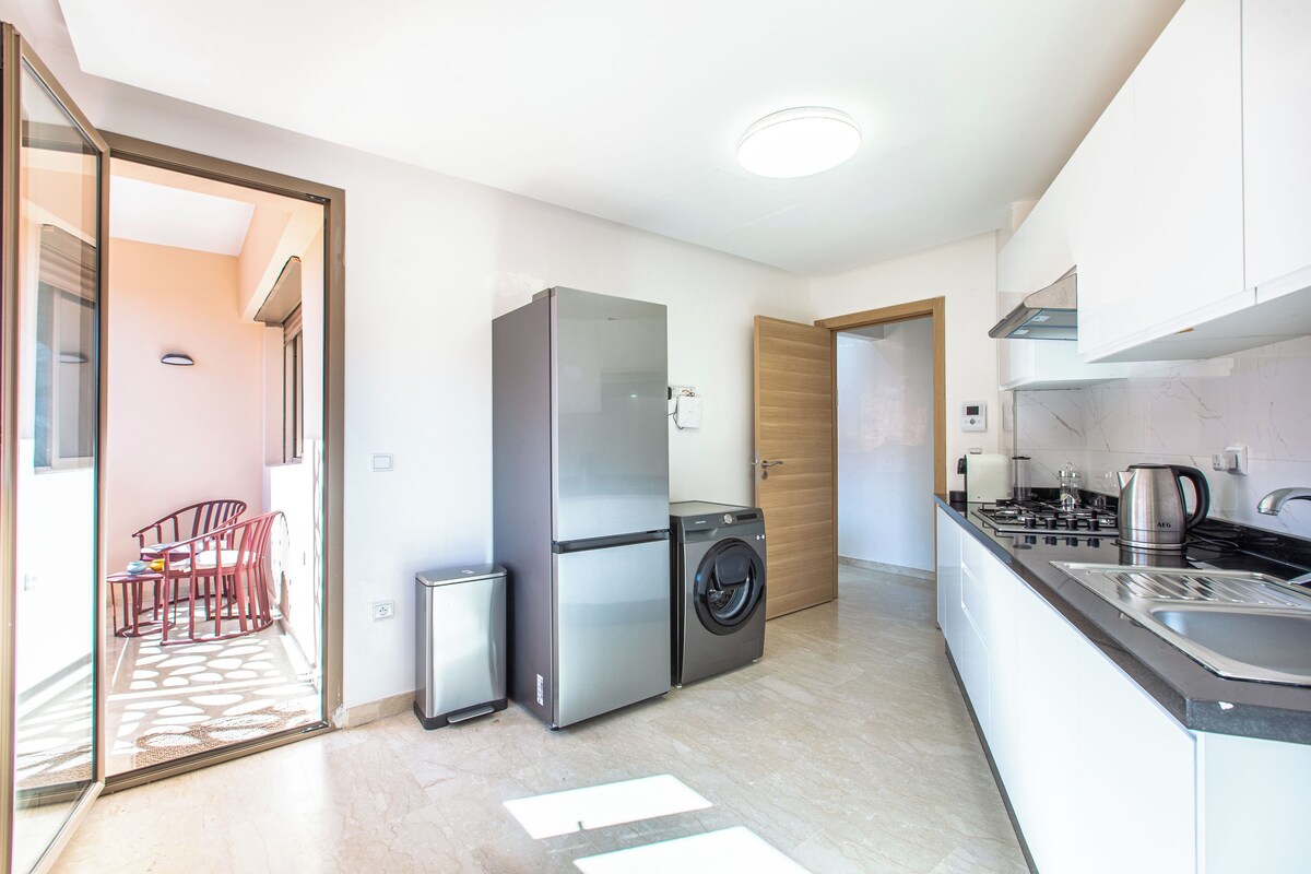 A compact kitchen with a refrigerator, washing machine, and a stove.