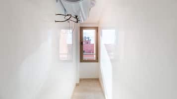 A narrow hallway with a door at the end leading outside.