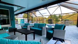A covered outdoor seating area with wicker furniture and a view of a swimming pool. - Turquoise Turtle - Private Heated Pool: Relax & Enjoy (Fort Pierce)