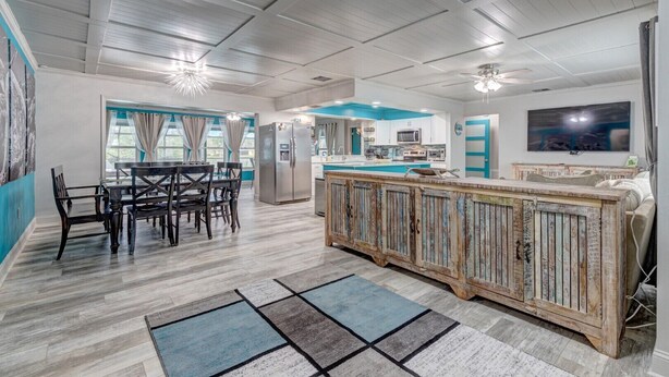 A spacious kitchen with a large island, a dining area with a table and chairs, and a living area with a TV and seating. - Turquoise Turtle - Private Heated Pool: Relax & Enjoy (Fort Pierce)
