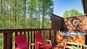 A wooden deck with red Adirondack chairs, a hot tub, and a decorative wall. - A Top Notch Lodge (Gatlinburg)