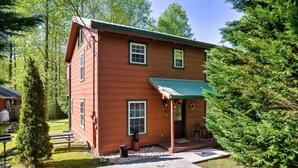 A two-story wooden cabin with a green awning, a porch, and a small front yard with a picnic table and a tree. - A Top Notch Lodge (Gatlinburg)
