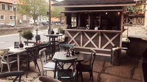 An outdoor seating area with tables and chairs, a bar counter, and a covered patio. - Aparthotel Alte Schmiede Dettelbach  (Dettelbach)
