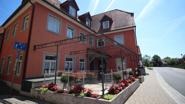 A red building with a sign reading "Alte Schmiede" and a covered entrance. - Aparthotel Alte Schmiede Dettelbach  (Dettelbach)