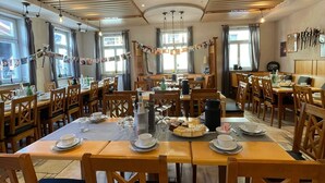 A dining area with wooden tables and chairs, a chandelier, and a view of the outdoors. - Aparthotel Alte Schmiede Dettelbach  (Dettelbach)