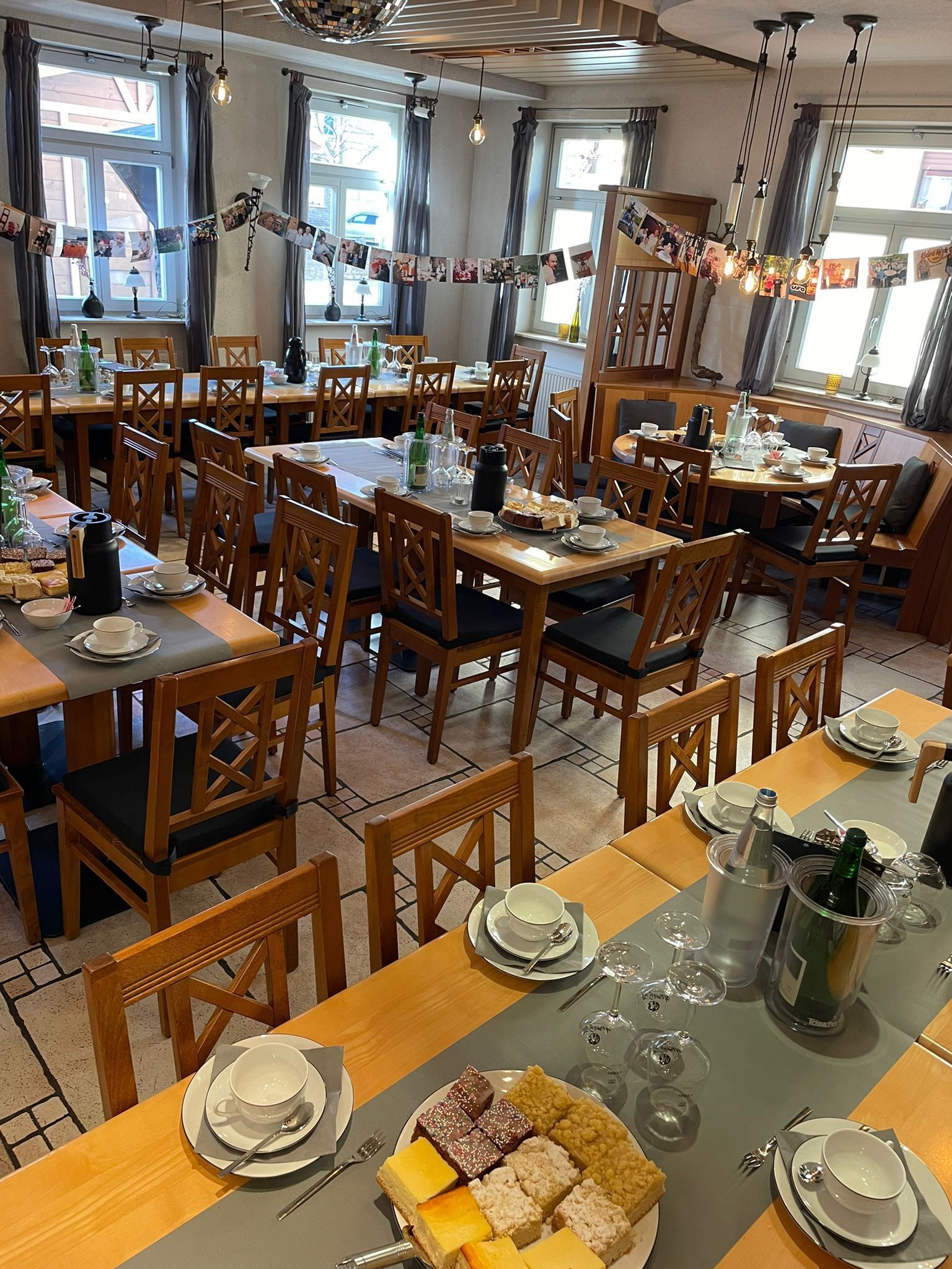 A dining area with multiple tables, chairs, and a variety of table settings including plates, cups, and cutlery.