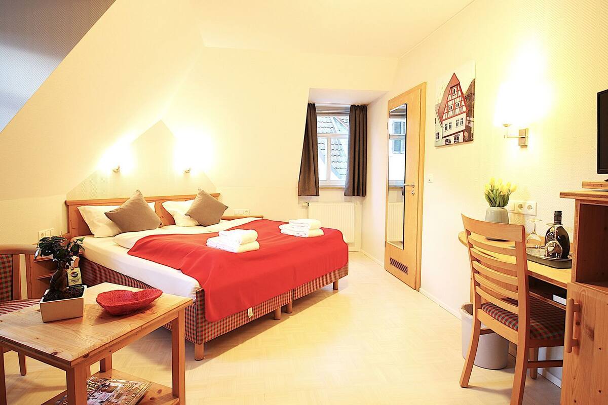 A bedroom with a bed, bedside tables, a desk, and a chair.