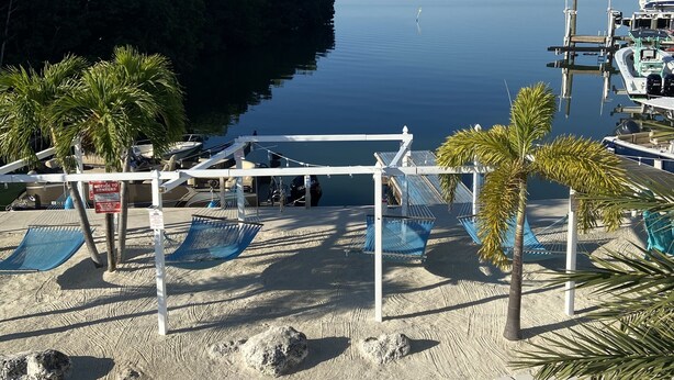 A beachside view with hammocks, a sandy area, and a marina with boats. - Corner of Paradise in Key Largo (Key Largo)