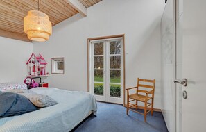 A bedroom with a bed, a chair, a window, and a door. - Cozy home in Gilleleje with WiFi (Gilleleje)