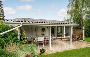 A covered patio area with a tiled roof, white walls, and a seating arrangement with chairs and tables. - Cozy home in Gilleleje with WiFi (Gilleleje)