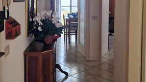 A hallway with a wooden console table, a potted plant, and a hanging light fixture. - SUMMER PROMOTION Summer apartment (Viareggio)