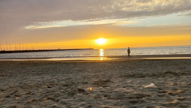 A beach with a person walking towards the sunset. - SUMMER PROMOTION Summer apartment (Viareggio)