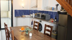 Ein Holzespeisesaal mit Stühlen, eine Küche mit Mikrowelle, Waschmaschine und Kühlschrank.