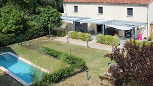 Ein zweistöckiges Haus mit Swimmingpool, überdachter Terrasse und gepflegtem Garten.