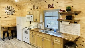 A compact kitchen with wooden cabinets, a sink, a stove, and a microwave. - UTV/ATV PARADISE! A/C and heat (Huntsville)