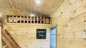 A wooden interior with a table and stools, a sign reading "Copperhead Cabins," and a window. - UTV/ATV PARADISE! A/C and heat (Huntsville)