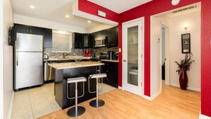 Una cocina moderna con una isla central, electrodomésticos de acero inoxidable y una pared de acento roja.