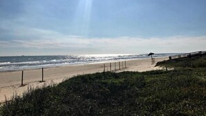 Una playa con un paseo de madera y una valla.
