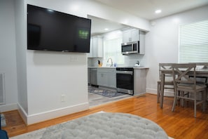 A modern kitchen with a flat-screen TV, stainless steel appliances, and a dining area with a wooden table and chairs. - Modern 2BR King Bed near USC, Downtown & Ft Jackson (Columbia)