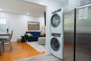 A compact living space with a washing machine, a dining area, and a sofa. - Modern 2BR King Bed near USC, Downtown & Ft Jackson (Columbia)