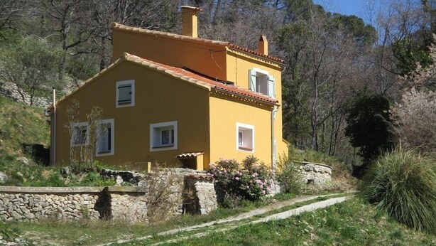 Una casa amarilla con un muro de piedra y una escalera de piedra que lleva a la entrada.