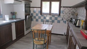 Una cocina con estufa a gas, horno y una ventana sobre el fregadero.