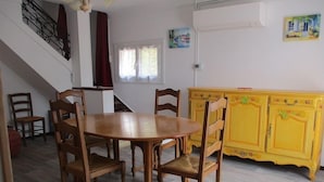 Un comedor con una mesa y sillas de madera, un armario amarillo y una escalera.
