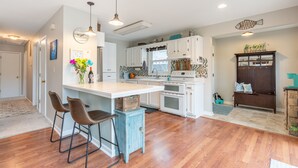 A modern kitchen with white cabinets, a central island, and bar stools. - Life on the Lake. Enjoy the peace and kayaks. (Locust Grove)