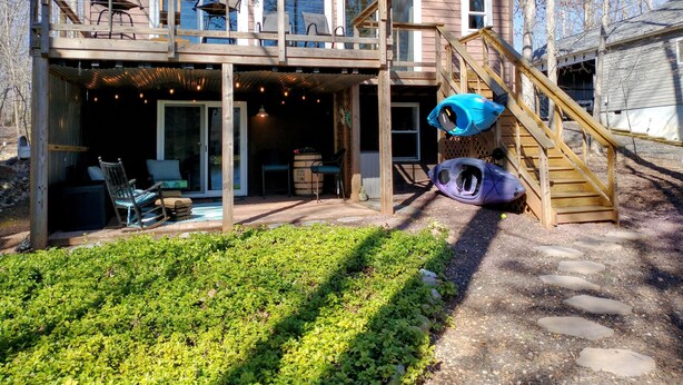A two-story house with a covered patio, outdoor seating, kayaks, and a wooden staircase. - Life on the Lake. Enjoy the peace and kayaks. (Locust Grove)
