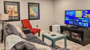 A living room with a sofa, a red chair, a coffee table, a TV, and a bookshelf. - Life on the Lake. Enjoy the peace and kayaks. (Locust Grove)