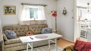 Een gezellige woonkamer met een bank, een klein wit tafeltje en een vloerlamp.