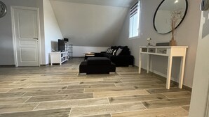 Ein modernes Wohnzimmer mit einem schwarzen Sofa, einem weißen Konsolentisch und einem großen Spiegel.