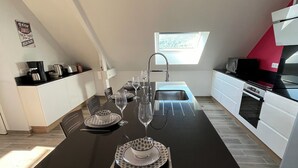 Eine moderne Küche mit Esstisch für vier Personen, eingebautem Ofen und einem Fenster für natürliches Licht.