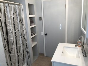 Un baño con un lavamanos blanco, un espejo y una puerta con interruptor de luz.
