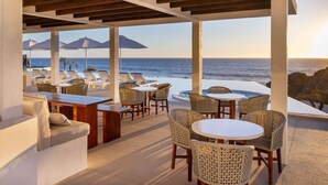 A covered outdoor seating area with tables and chairs, overlooking the ocean. - Oceanfront at Cerritos Beach • Infinity Pool+Spa (Los Cerritos)