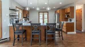 Una cocina moderna con una isla central, iluminación colgante y armarios de madera.